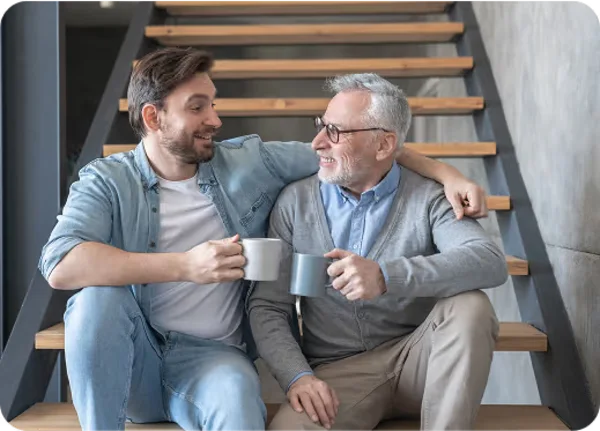 An older man and his adult son sharing coffee and a laugh